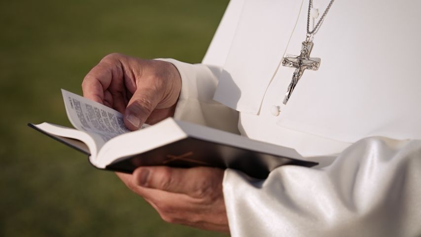 Papież senior trzyma książeczkę z modlitwami.